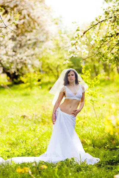 Junge Frau posiert in weißen Dessous und Rock aus einem großen Stück weißen Tuchs — Stockfoto