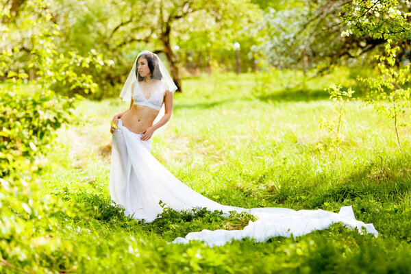Young woman posing in white lingerie, veil and skirt of a large piece of white cloth