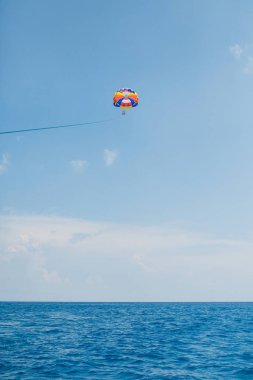 Motorlu bir tekne ile çekili renkli paraşüt uçan insanlar
