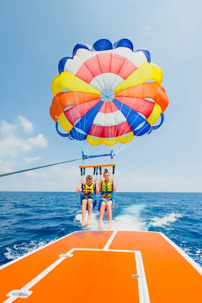 Casal de turistas prepearing para voar em um paraquedas multi colorido — Fotografia de Stock