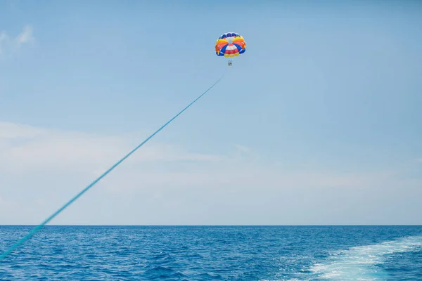 Gente volando en un colorido paracaídas remolcado por un barco a motor — Foto de Stock