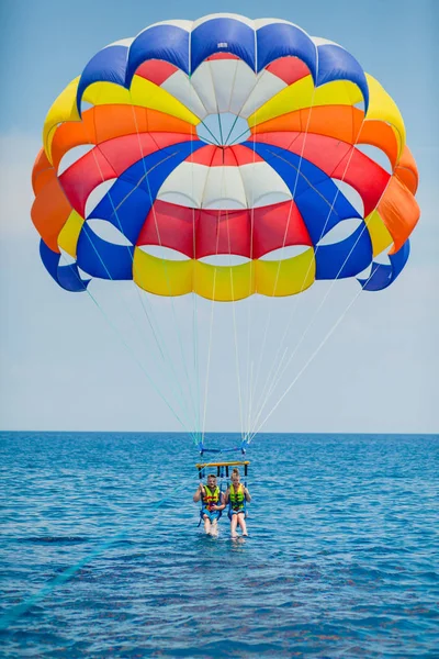 Pareja de turistas volando en un colorido paracaídas — Foto de Stock