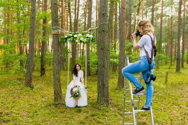 Professional wedding photographer using stepladder to make pictures of the bride