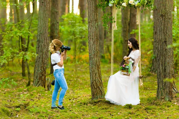 Fotograf ślubny robienia zdjęć panny młodej na liny huśtawka — Zdjęcie stockowe