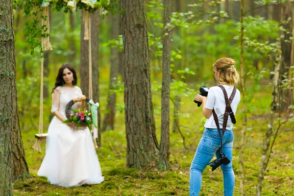 Fotograf ślubny robienia zdjęć panny młodej na liny huśtawka — Zdjęcie stockowe