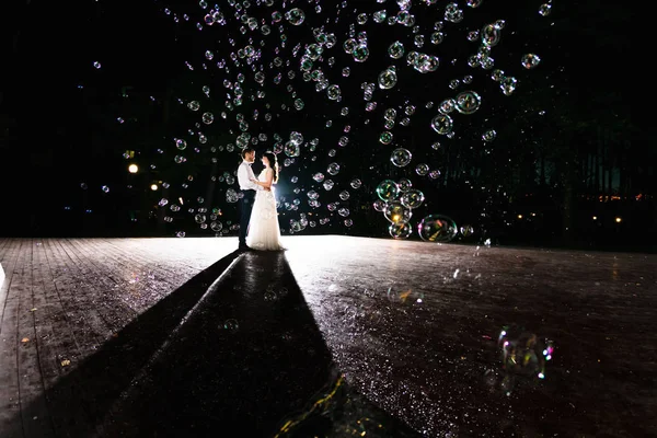 Casal de recém-casados na escuridão no fundo do flash de luz — Fotografia de Stock