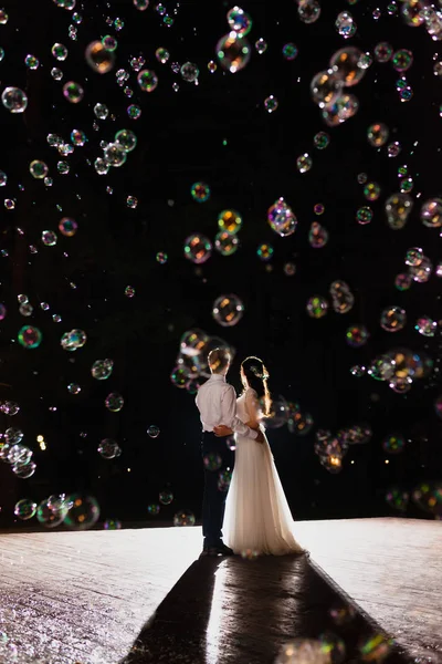 Couple de jeunes mariés dans l'obscurité à l'arrière-plan du flash de lumière — Photo