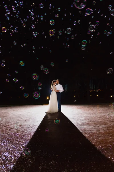 Paar pasgetrouwden in de duisternis op de achtergrond van de flits van licht — Stockfoto