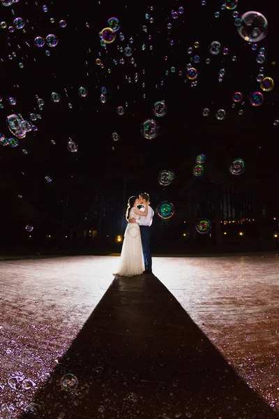 Un par de recién casados y una enorme cantidad de burbujas están volando en el aire — Foto de Stock