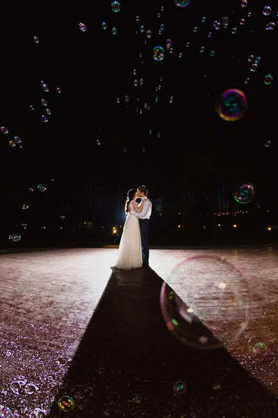 Casal de recém-casados e enorme quantidade de bolhas estão voando no ar — Fotografia de Stock