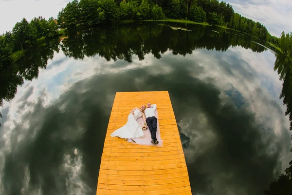 Coppia di sposi novelli e superficie del lago con riflesso di cielo nuvoloso — Foto Stock