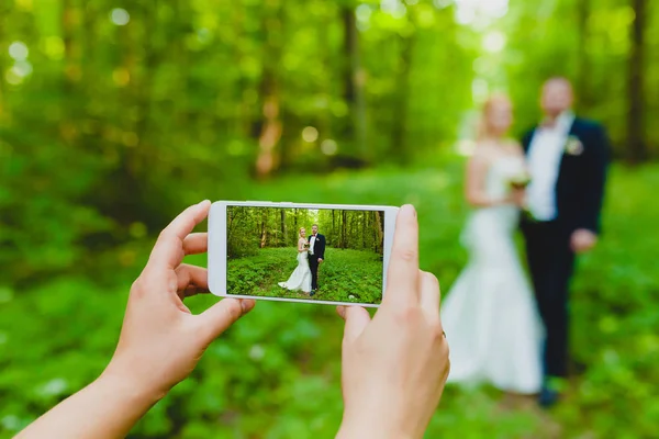 Quelqu'un utilise un smartphone pour faire une photo de jeunes mariés — Photo