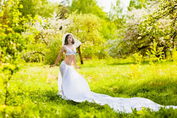 Junge Frau posiert in weißen Dessous und Rock aus einem großen Stück weißen Tuchs — Stockfoto