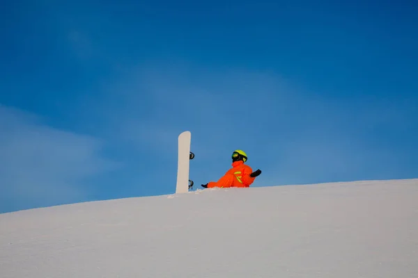 A tetején a sípálya mellett ül fehér snowboard snowboardos freerider — Stock Fotó