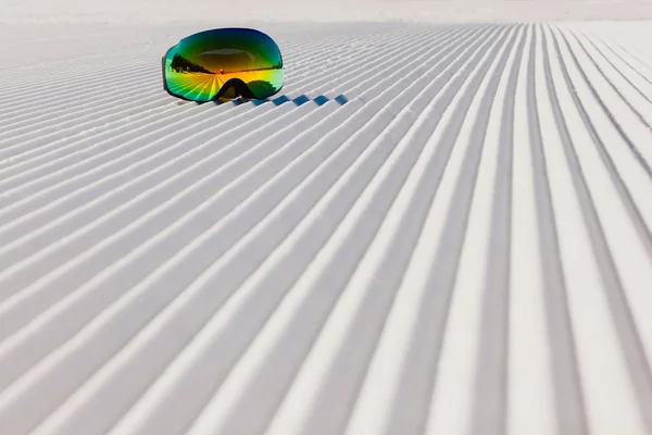 Ski goggles laying on a new groomed snow and empty ski slope — Stock Photo, Image
