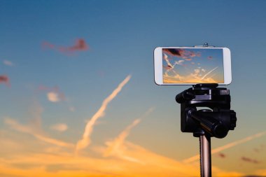 Smartphone çarpıcı gün batımından görüntü yakalama tripod üzerinde