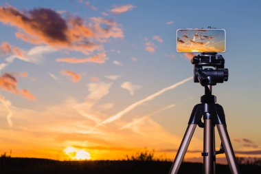 Smartphone çarpıcı gün batımından görüntü yakalama tripod üzerinde