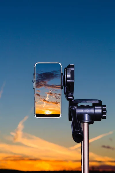 Смартфон на штатив захоплення зображення заходу сонця у вертикальному режимі — стокове фото