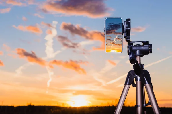 Smartphone en trípode captura de imagen de puesta del sol en modo vertical — Foto de Stock