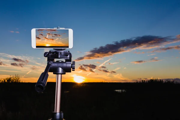 Smartphone en trípode captura de imagen de la puesta del sol impresionante — Foto de Stock