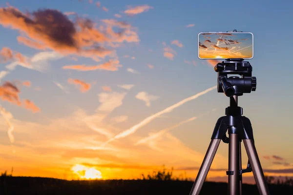 Smartphone çarpıcı gün batımından görüntü yakalama tripod üzerinde