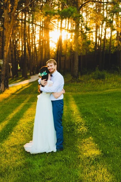 Casal de recém-casados em pé em uma grama verde — Fotografia de Stock