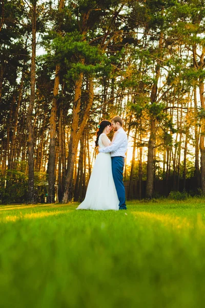 Couple de jeunes mariés debout sur une herbe verte — Photo