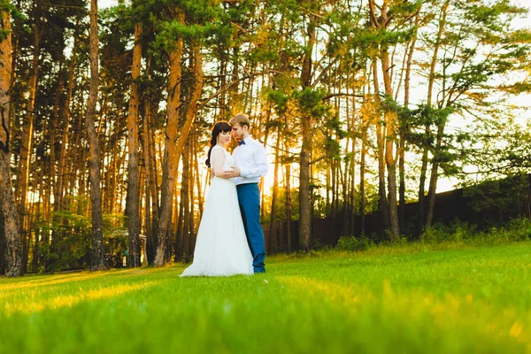 Casal de recém-casados em pé em uma grama verde — Fotografia de Stock