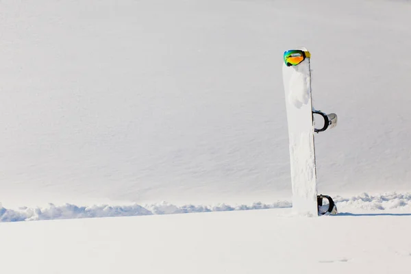 Snowboard y esquí googles tendidos en una nieve cerca de la pendiente freeride —  Fotos de Stock