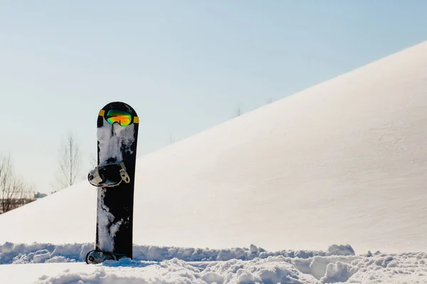 Snowboard und Skibrille auf Schnee in der Nähe der Freeride-Piste — Stockfoto