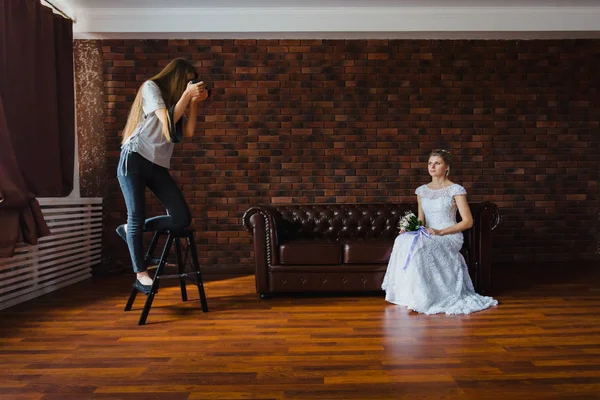 Photographe prenant des photos de la mariée en studio sur un grand canapé en cuir — Photo