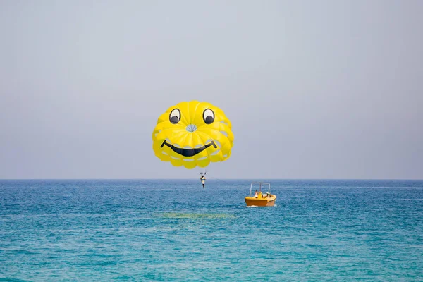 Femme volant sur un parachute jaune avec un visage souriant dessus — Photo