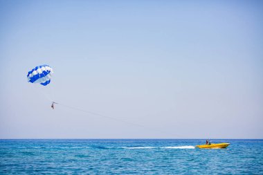 Birkaç turist mavi beyaz bir paraşütle uçuyor.