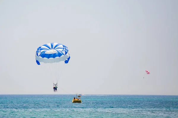 Couple of tourists flies on a blue and white parachute — Stock Photo, Image