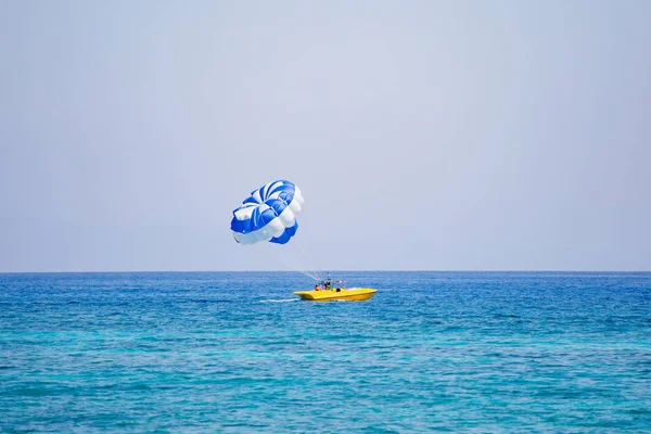 Pareja de turistas vuela en un paracaídas azul y blanco — Foto de Stock