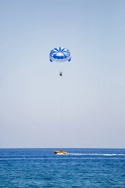 Paar Touristen fliegt an einem blau-weißen Fallschirm — Stockfoto