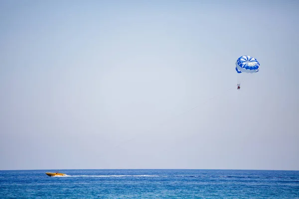 Pareja de turistas vuela en un paracaídas azul y blanco — Foto de Stock