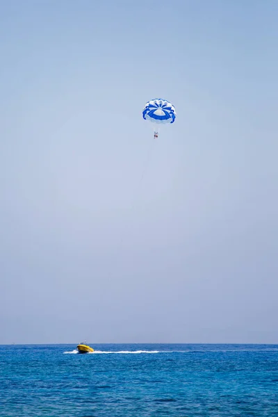 観光客のカップルは、青と白のパラシュートで飛ぶ — ストック写真