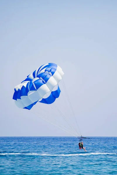 Par turister flyger på en blå och vit fallskärm — Stockfoto