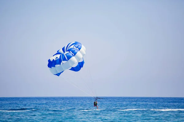 Paar Touristen fliegt an einem blau-weißen Fallschirm — Stockfoto
