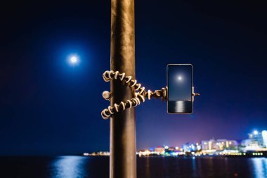 Deniz gece manzara fotoğraf yapmak için esnek tripod üzerinde akıllı telefon kullanma