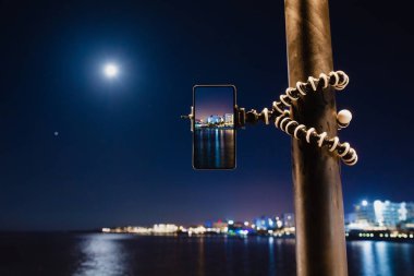 Deniz gece manzara fotoğraf yapmak için esnek tripod üzerinde akıllı telefon kullanma