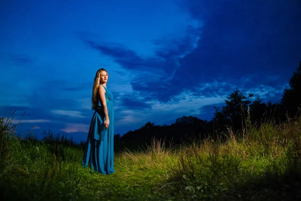 Vacker blond modell i blå luft klänning poserar på den gröna ängen — Stockfoto