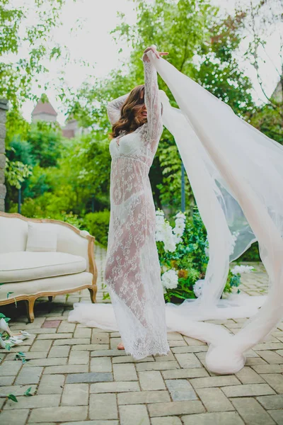 Verleidelijke jonge bruid in wit neglige dansen met groot stukje witte stof — Stockfoto