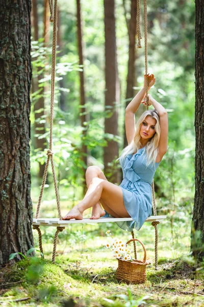 Красивая блондинка в синем платье позирует на качелях — стоковое фото