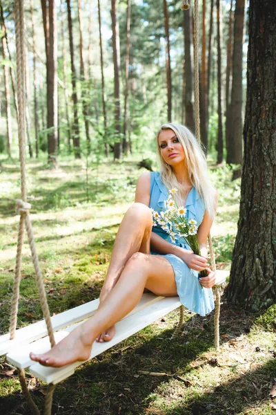 Красивая блондинка в синем платье позирует с букетом ромашки — стоковое фото