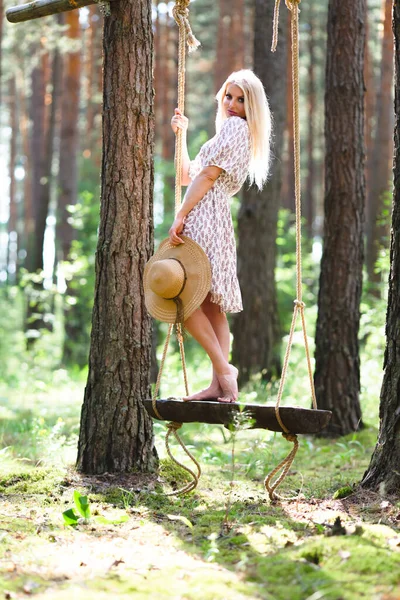 Blond vrouw met slanke mooie naakte benen staan met op een touw swing — Stockfoto