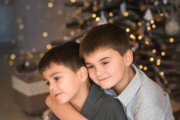 Two boys - brothers hug on background of Christmas lights. New year theme.