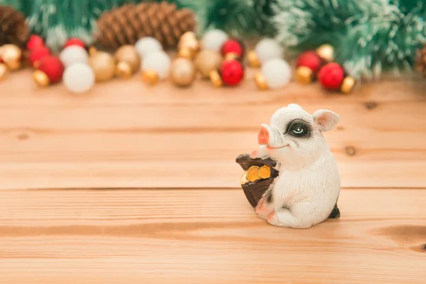 Ceramic pig with money box on wooden  background with Christmas ornaments, selective focus. New year backdrop with copy space for cards, posters and invitation.