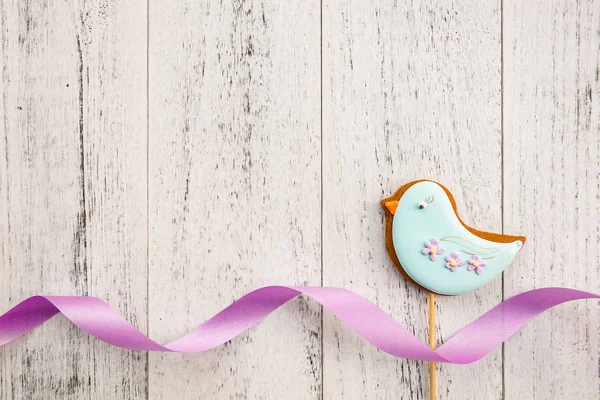 Easter cookie blue bird and violet ribbon on white wooden table with copy space. Spring Baking